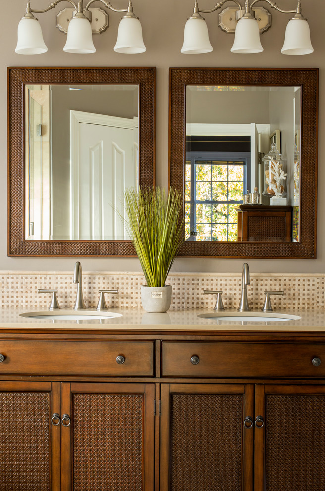 Diseño de cuarto de baño costero con puertas de armario de madera en tonos medios, paredes beige, lavabo bajoencimera y espejo con luz