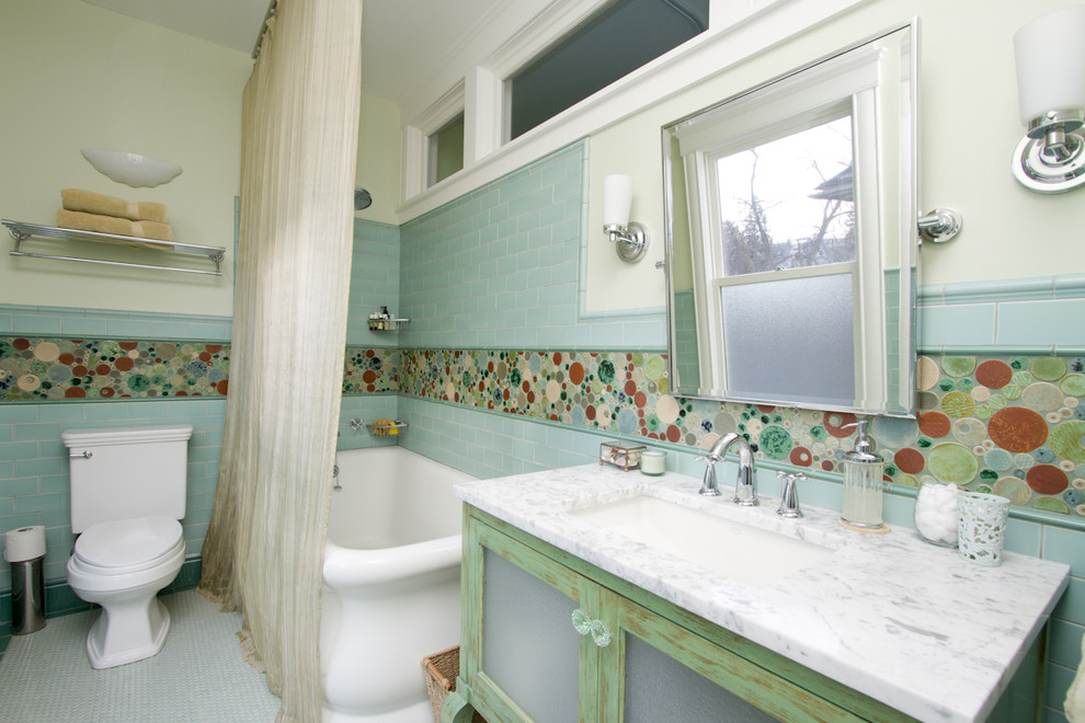 Exempel på ett maritimt badrum, med ett undermonterad handfat, luckor med glaspanel, skåp i slitet trä, en dusch/badkar-kombination, en toalettstol med separat cisternkåpa, marmorbänkskiva, flerfärgad kakel och mosaik