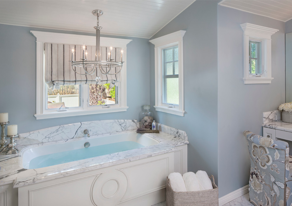 Example of a beach style master white tile bathroom design in Los Angeles with blue walls and an undermount tub