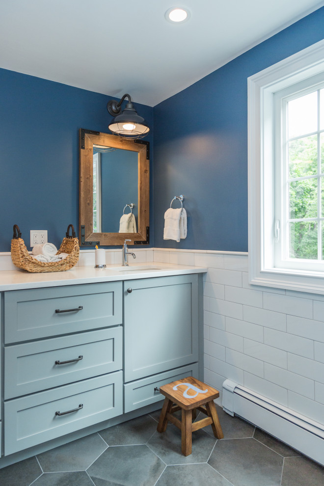 Bild på ett mellanstort maritimt vit vitt badrum för barn, med skåp i shakerstil, blå skåp, ett badkar i en alkov, blå kakel, ett undermonterad handfat, bänkskiva i akrylsten och grått golv