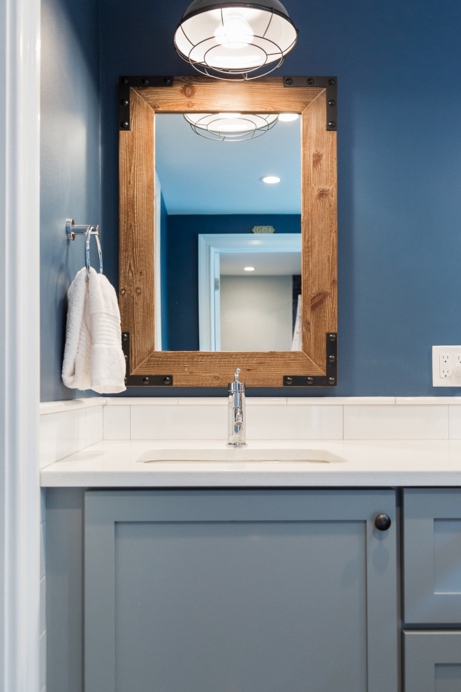 Aménagement d'une salle de bain bord de mer de taille moyenne pour enfant avec un placard à porte shaker, des portes de placard bleues, une baignoire en alcôve, un carrelage bleu, un lavabo encastré, un plan de toilette en surface solide, un sol gris et un plan de toilette blanc.