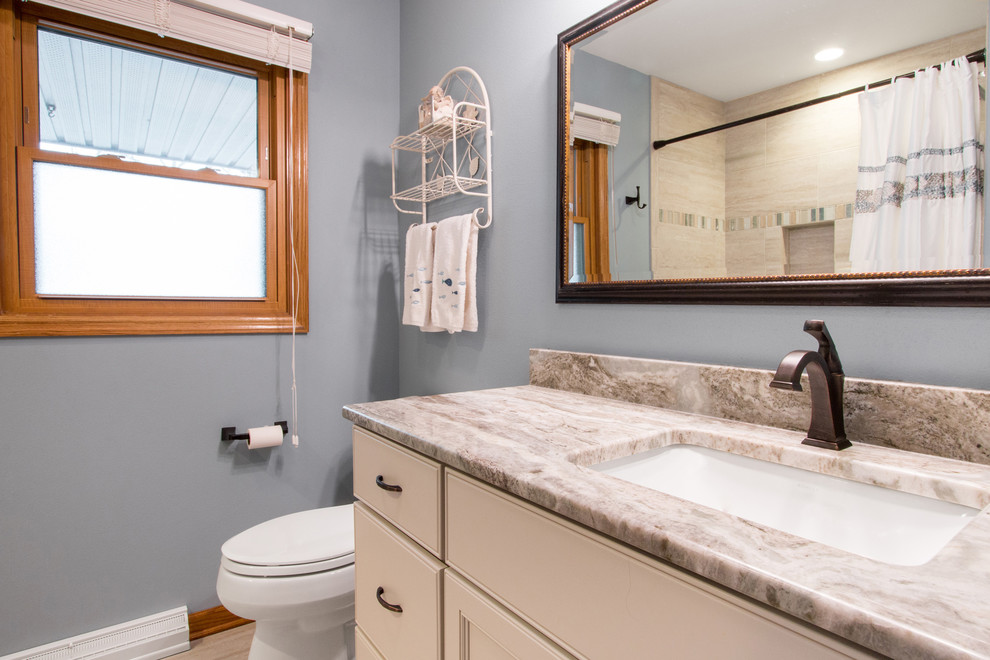Maritim inredning av ett litet beige beige badrum, med luckor med infälld panel, vita skåp, ett badkar i en alkov, en dusch/badkar-kombination, en toalettstol med hel cisternkåpa, beige kakel, keramikplattor, blå väggar, klinkergolv i keramik, ett undermonterad handfat, granitbänkskiva, beiget golv och dusch med duschdraperi