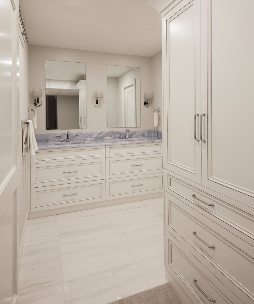 Inredning av ett maritimt blå blått en-suite badrum, med luckor med infälld panel, vita skåp, en dusch i en alkov, en vägghängd toalettstol, blå kakel, glaskakel, grå väggar, marmorgolv, ett undermonterad handfat, marmorbänkskiva, vitt golv och dusch med skjutdörr