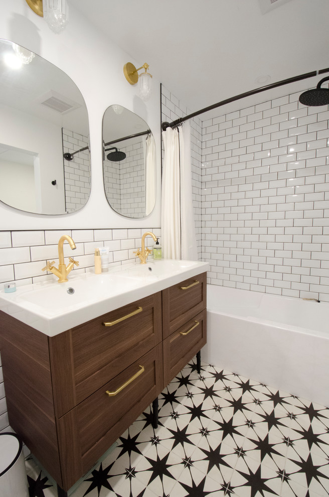 トロントにあるお手頃価格の中くらいなコンテンポラリースタイルのおしゃれなマスターバスルーム (シェーカースタイル扉のキャビネット、中間色木目調キャビネット、アルコーブ型浴槽、シャワー付き浴槽	、分離型トイレ、白いタイル、セラミックタイル、白い壁、セメントタイルの床、一体型シンク、人工大理石カウンター、白い床、シャワーカーテン、白い洗面カウンター) の写真