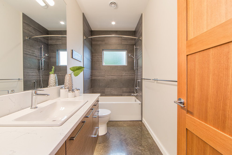 Inspiration for a medium sized contemporary ensuite bathroom in Vancouver with flat-panel cabinets, medium wood cabinets, an alcove bath, a walk-in shower, a two-piece toilet, grey tiles, ceramic tiles, white walls, concrete flooring, a built-in sink, quartz worktops, grey floors, a sliding door and white worktops.