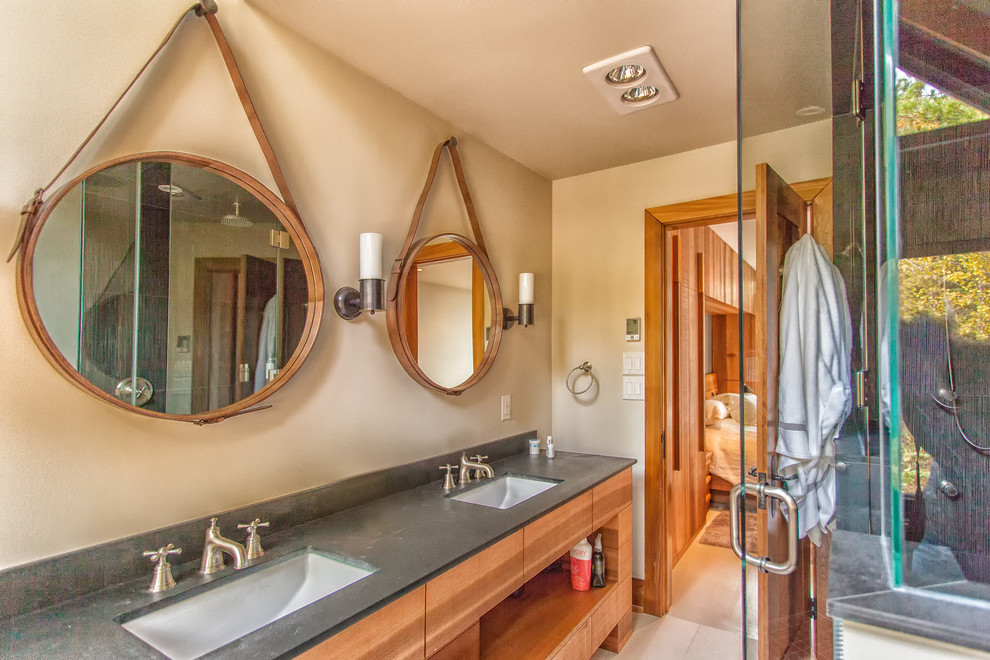 Exemple d'une salle de bain montagne en bois brun de taille moyenne avec un lavabo encastré, un placard à porte plane, un plan de toilette en granite, un carrelage gris et un mur beige.