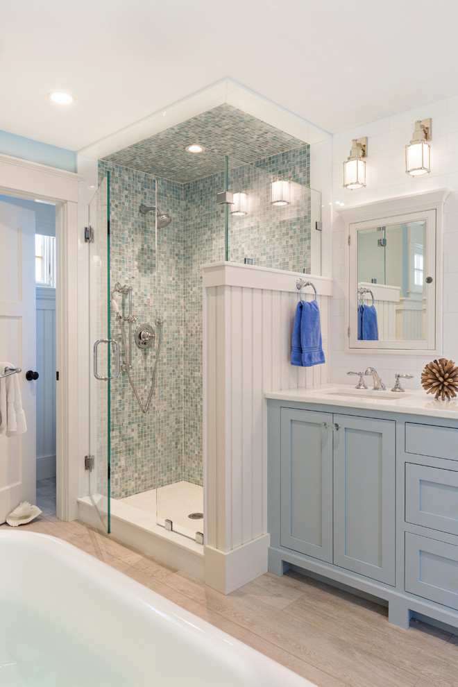 Пример оригинального дизайна: главная ванная комната в морском стиле с фасадами с утопленной филенкой, синими фасадами, отдельно стоящей ванной, угловым душем, белыми стенами и врезной раковиной