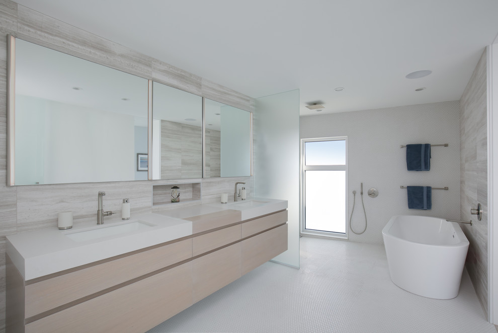 На фото: большая главная ванная комната в морском стиле с плоскими фасадами, светлыми деревянными фасадами, отдельно стоящей ванной, душем без бортиков, инсталляцией, разноцветной плиткой, плиткой из известняка, разноцветными стенами, полом из мозаичной плитки, врезной раковиной, столешницей из искусственного кварца, белым полом, открытым душем и белой столешницей с