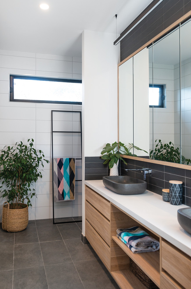 Mid-sized beach style master black and white tile and mosaic tile porcelain tile and gray floor doorless shower photo in Other with recessed-panel cabinets, light wood cabinets, white walls, a vessel sink, quartz countertops and white countertops