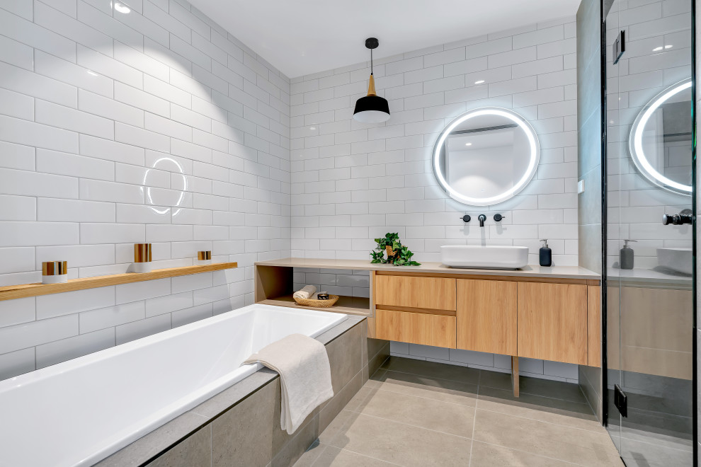 На фото: главная ванная комната среднего размера в современном стиле с плоскими фасадами, оранжевыми фасадами, накладной ванной, душем в нише, унитазом-моноблоком, белой плиткой, керамогранитной плиткой, белыми стенами, полом из керамогранита, настольной раковиной, столешницей из искусственного кварца, серым полом, душем с распашными дверями, серой столешницей, нишей, тумбой под одну раковину и подвесной тумбой