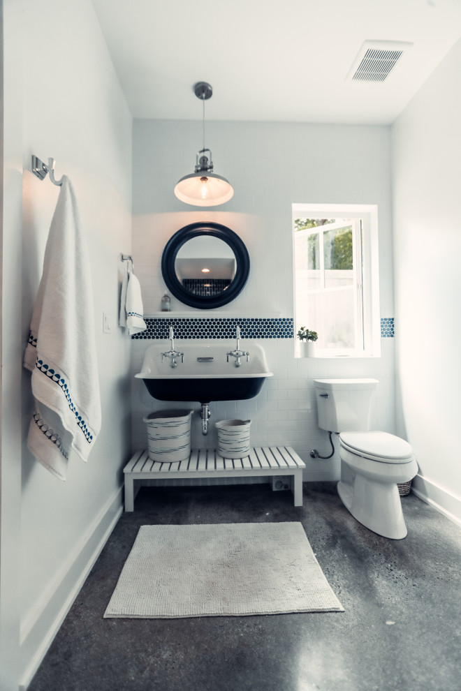 This is an example of a medium sized coastal family bathroom in Other with white cabinets, a two-piece toilet, blue tiles, glass tiles, white walls, concrete flooring, a trough sink, a hinged door, a single sink and a floating vanity unit.