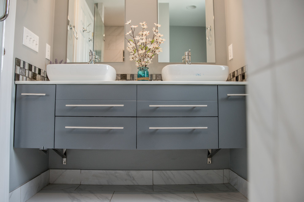 Modern inredning av ett mellanstort en-suite badrum, med släta luckor, grå skåp, grå väggar, marmorgolv, ett fristående handfat, bänkskiva i akrylsten och glaskakel