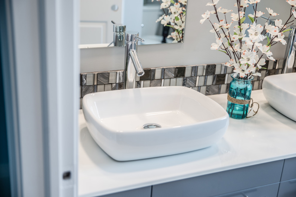 Exempel på ett mellanstort modernt en-suite badrum, med släta luckor, grå skåp, en dusch i en alkov, en toalettstol med separat cisternkåpa, grå kakel, grå väggar, marmorgolv, ett fristående handfat, glaskakel och bänkskiva i akrylsten