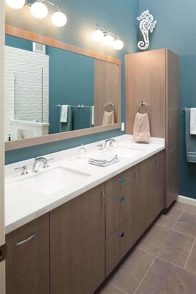 Large beach style ensuite bathroom in San Francisco with a submerged sink, flat-panel cabinets, medium wood cabinets, solid surface worktops, an alcove bath, a shower/bath combination, a two-piece toilet, grey tiles, porcelain tiles, blue walls and porcelain flooring.