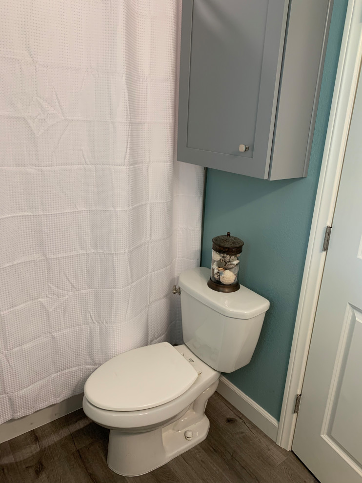 Réalisation d'un WC et toilettes marin de taille moyenne avec un placard à porte shaker, des portes de placard grises, WC à poser, un carrelage blanc, des carreaux de porcelaine, un mur bleu, un sol en vinyl, un lavabo encastré, un plan de toilette en quartz modifié, un sol gris, un plan de toilette blanc et meuble-lavabo encastré.