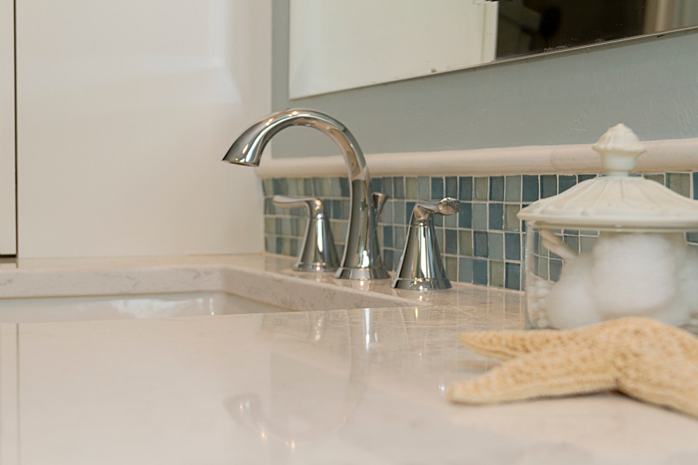 Modelo de cuarto de baño costero pequeño con armarios estilo shaker, puertas de armario blancas, ducha empotrada, sanitario de una pieza, baldosas y/o azulejos azules, baldosas y/o azulejos de cemento, paredes azules, suelo de baldosas de terracota, aseo y ducha, lavabo bajoencimera y encimera de laminado