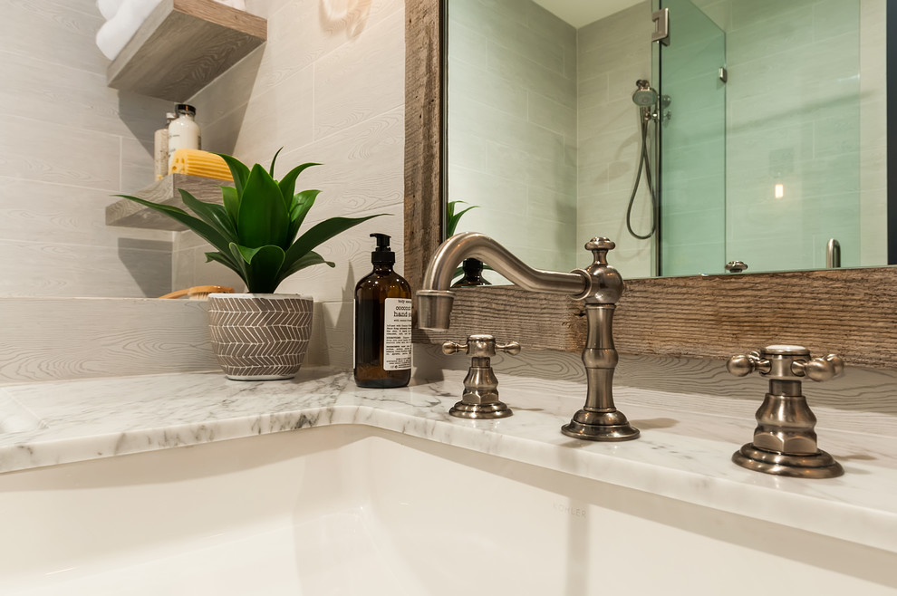Foto på ett mellanstort maritimt vit badrum med dusch, med luckor med infälld panel, blå skåp, en dusch i en alkov, grå kakel, keramikplattor, grå väggar, ett undermonterad handfat, marmorbänkskiva och med dusch som är öppen