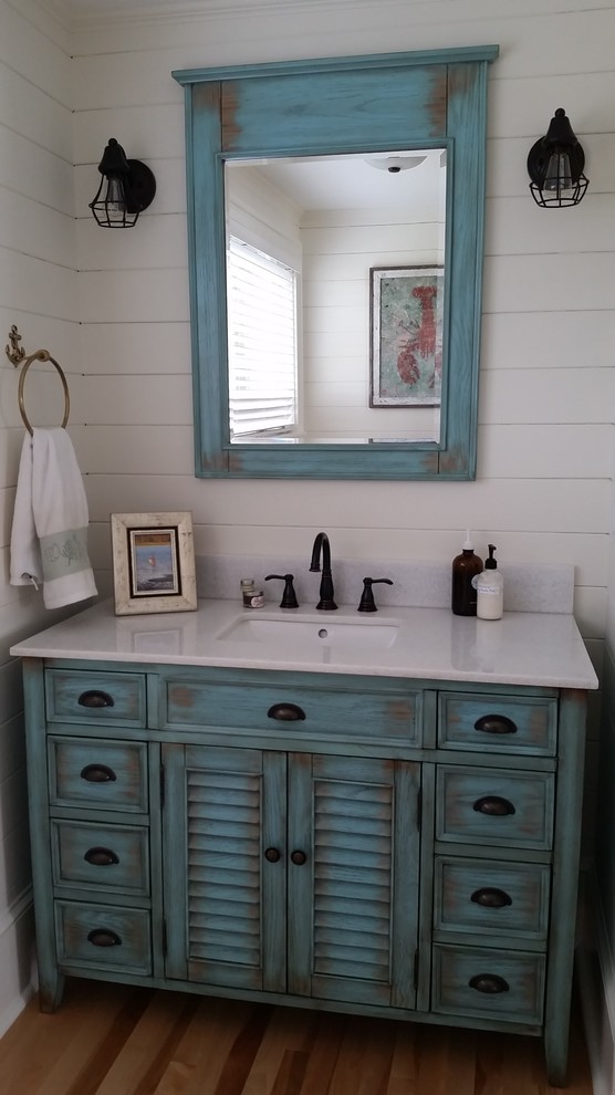 Kleines Maritimes Duschbad mit verzierten Schränken, blauen Schränken, Toilette mit Aufsatzspülkasten, weißer Wandfarbe, hellem Holzboden und Unterbauwaschbecken in Boston