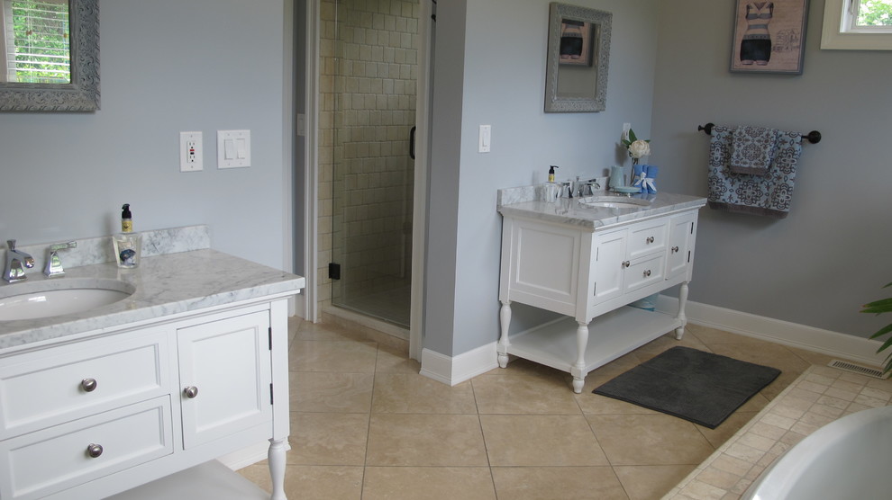 Inredning av ett maritimt stort en-suite badrum, med ett undermonterad handfat, möbel-liknande, vita skåp, marmorbänkskiva, ett platsbyggt badkar, en dusch i en alkov, en toalettstol med separat cisternkåpa, beige kakel, stenkakel, blå väggar och travertin golv