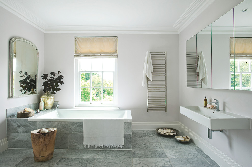 Foto på ett funkis badrum, med ett väggmonterat handfat, ett platsbyggt badkar, grå kakel, stenkakel och grå väggar
