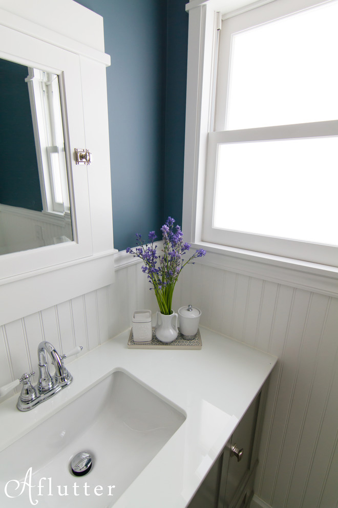 Idée de décoration pour une petite salle de bain craftsman avec un placard à porte shaker, des portes de placard grises, un plan de toilette en surface solide, un carrelage blanc, des carreaux de céramique, un mur bleu et un sol en carrelage de porcelaine.