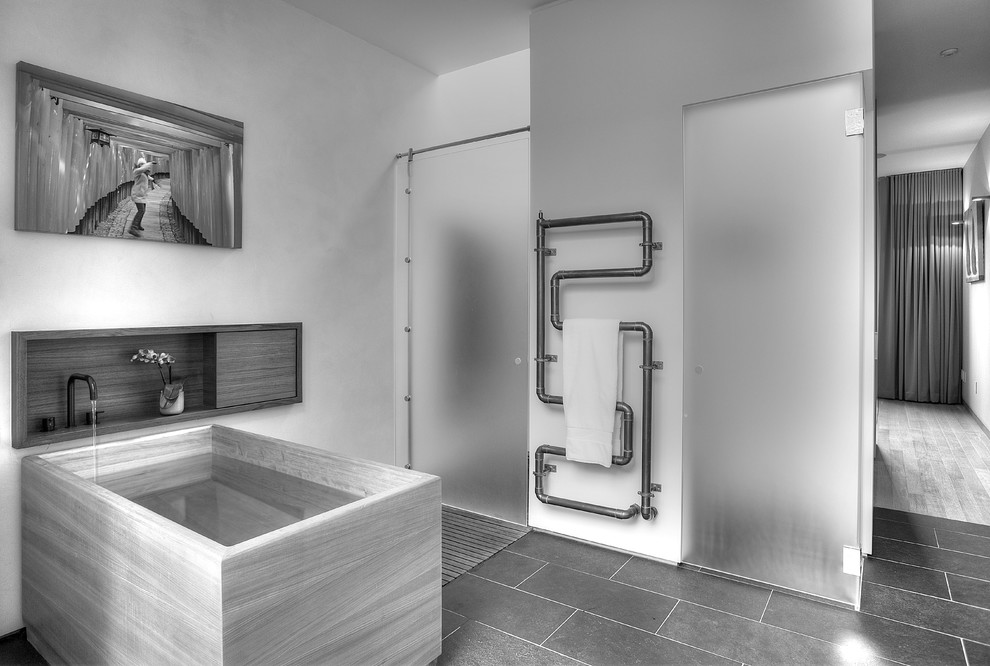 На фото: главная ванная комната среднего размера в современном стиле с черным полом, отдельно стоящей ванной, душем в нише, душем с распашными дверями, плоскими фасадами, инсталляцией, полом из сланца, монолитной раковиной и столешницей из искусственного камня