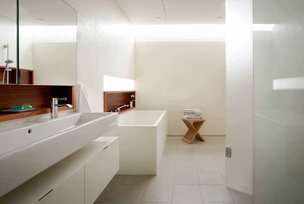Photo of a large contemporary ensuite bathroom in Boston with a freestanding bath, a walk-in shower, a wall mounted toilet, a wall-mounted sink, an open shower, flat-panel cabinets, white cabinets, white walls, porcelain flooring and beige floors.
