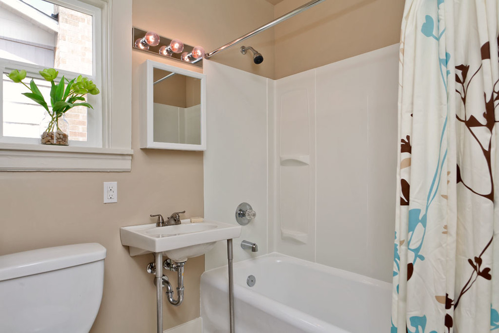 Modelo de cuarto de baño infantil clásico con bañera encastrada, sanitario de dos piezas, paredes beige y lavabo suspendido