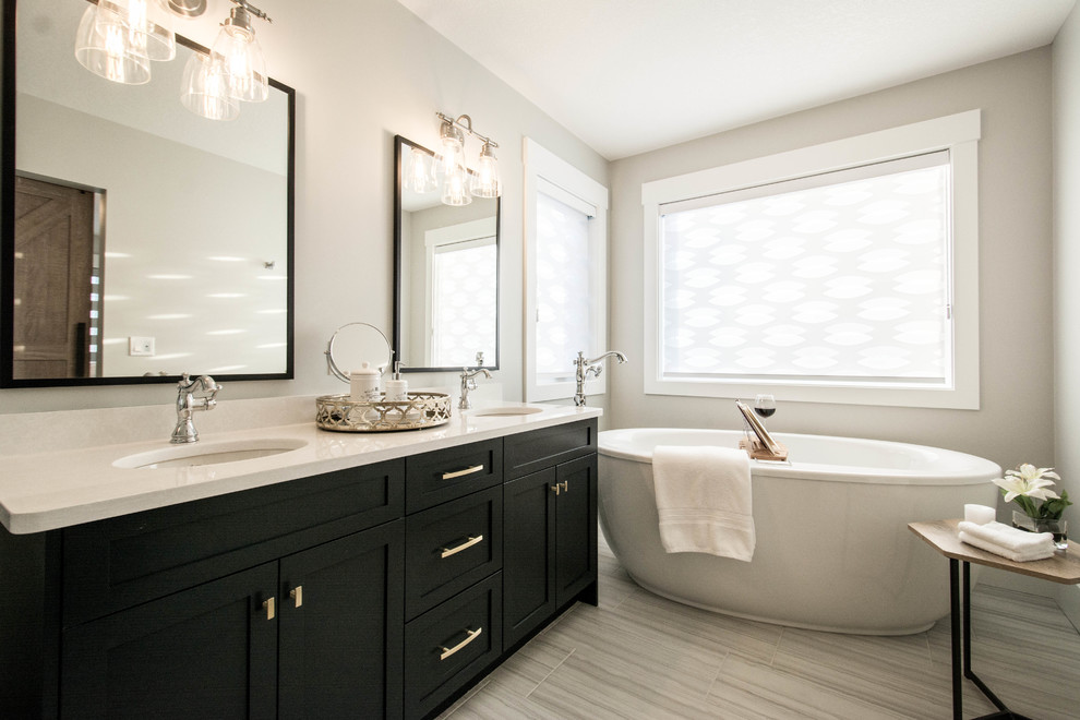 Inspiration for a medium sized traditional ensuite bathroom in Calgary with shaker cabinets, black cabinets, a freestanding bath, beige walls, laminate floors, a submerged sink, quartz worktops, beige floors, white worktops, an alcove shower, beige tiles, porcelain tiles and a hinged door.