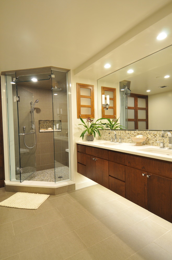 Inspiration pour une salle de bain principale design en bois brun de taille moyenne avec un lavabo encastré, un placard en trompe-l'oeil, un plan de toilette en surface solide, une douche d'angle, WC à poser, un carrelage beige, un carrelage en pâte de verre, un mur beige, un sol en carrelage de céramique, un sol gris, une cabine de douche à porte battante et un plan de toilette blanc.