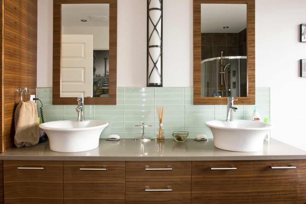 Immagine di una stanza da bagno design con lavabo a bacinella, ante lisce, ante in legno bruno, piastrelle blu, piastrelle di vetro e top grigio
