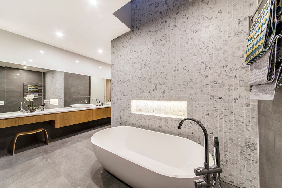 Источник вдохновения для домашнего уюта: главная ванная комната в современном стиле с плоскими фасадами, светлыми деревянными фасадами, отдельно стоящей ванной, серой плиткой и настольной раковиной