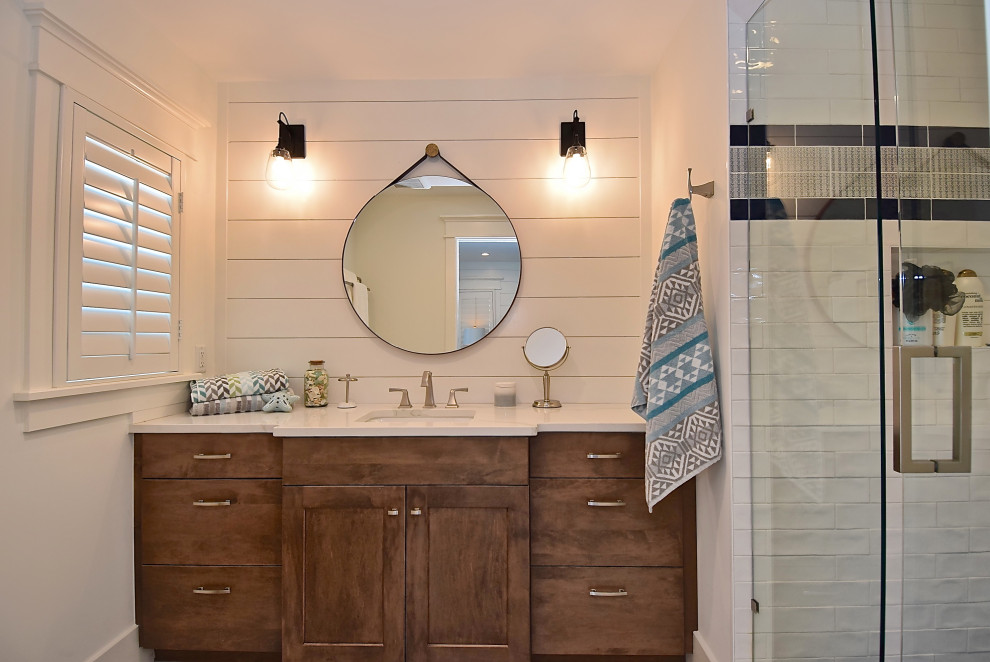 Alcove shower - large coastal white tile and porcelain tile porcelain tile and blue floor alcove shower idea in Tampa with shaker cabinets, medium tone wood cabinets, a one-piece toilet, white walls, an undermount sink, quartz countertops, a hinged shower door and white countertops