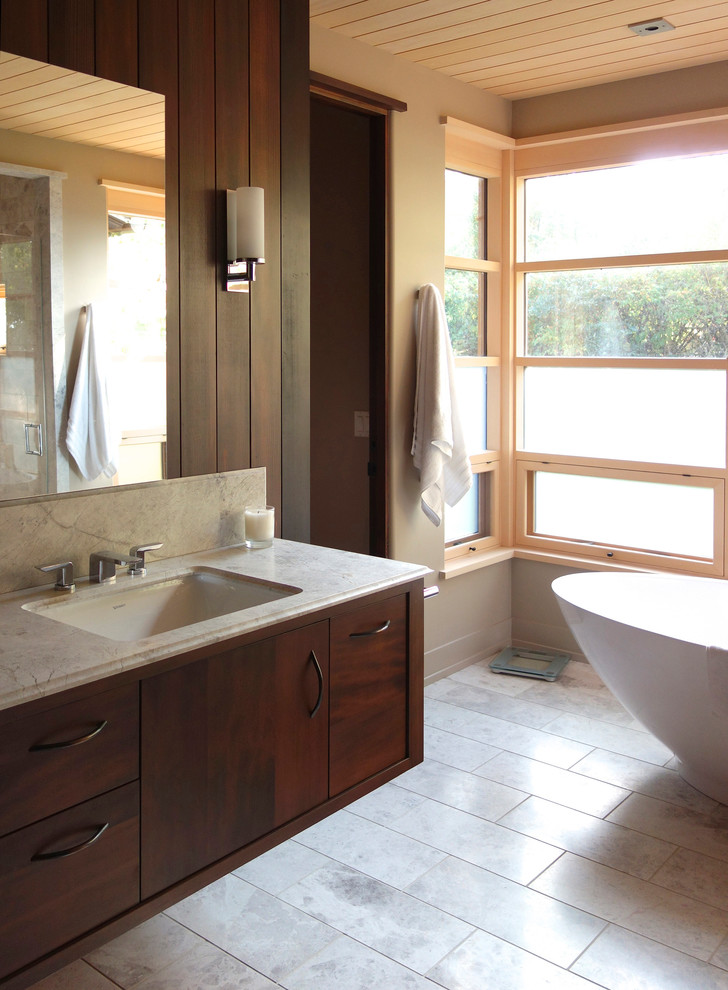 Ispirazione per una stanza da bagno design con ante lisce, vasca freestanding, pareti grigie, lavabo sottopiano, pavimento grigio, top beige e ante in legno bruno