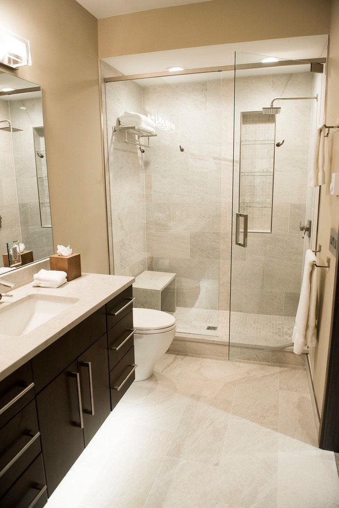 Mid-sized trendy master beige tile and porcelain tile porcelain tile and beige floor bathroom photo in Denver with flat-panel cabinets, black cabinets, a two-piece toilet, beige walls, an undermount sink and marble countertops