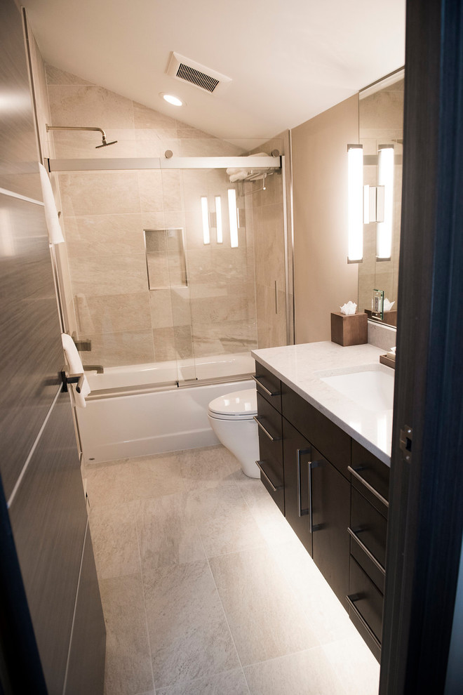 Cette photo montre une salle de bain principale tendance de taille moyenne avec un placard à porte plane, des portes de placard noires, une baignoire en alcôve, un combiné douche/baignoire, WC séparés, un carrelage beige, des carreaux de porcelaine, un mur beige, un sol en carrelage de porcelaine, un lavabo encastré, un plan de toilette en marbre, un sol beige et une cabine de douche à porte coulissante.