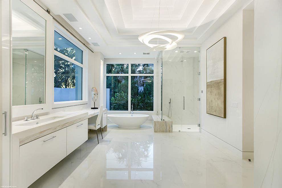 Inspiration for a large contemporary ensuite bathroom in Miami with flat-panel cabinets, white cabinets, a freestanding bath, a corner shower, grey tiles, white tiles, stone tiles, white walls, marble flooring, a submerged sink, white floors and a hinged door.