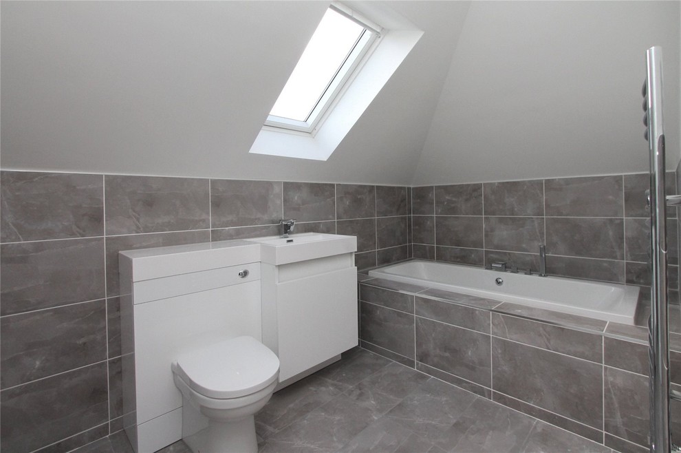 Medium sized contemporary family bathroom in Glasgow with freestanding cabinets, white cabinets, a built-in bath, a two-piece toilet, grey tiles, porcelain tiles, white walls, porcelain flooring and a built-in sink.