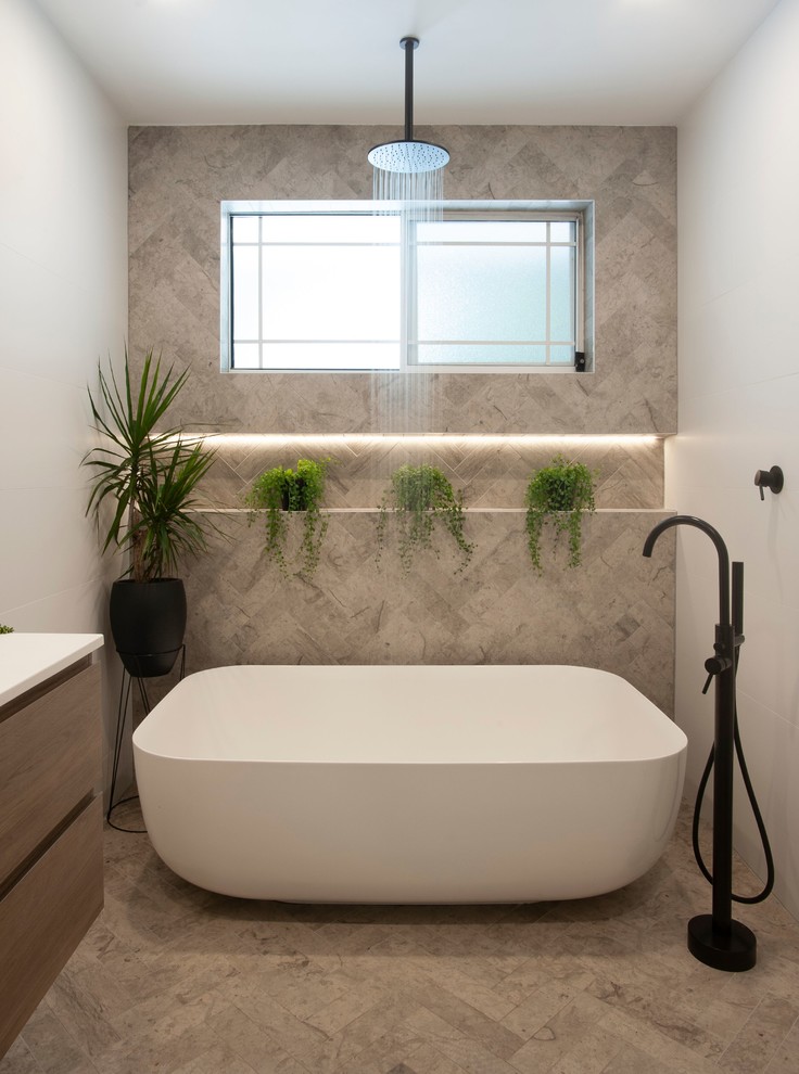 Идея дизайна: ванная комната среднего размера в современном стиле с фасадами цвета дерева среднего тона, отдельно стоящей ванной, душем над ванной, биде, серой плиткой, каменной плиткой, серыми стенами, паркетным полом среднего тона, столешницей из искусственного камня, серым полом и открытым душем