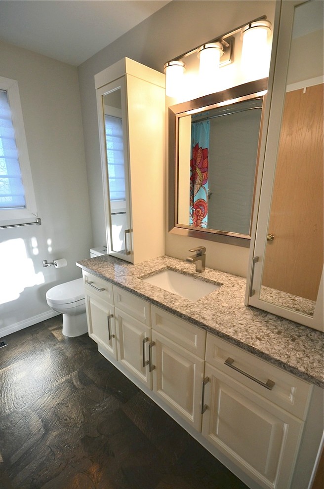 Modelo de cuarto de baño tradicional renovado de tamaño medio con lavabo bajoencimera, armarios con paneles con relieve, puertas de armario blancas, encimera de cuarzo compacto, sanitario de dos piezas y paredes grises