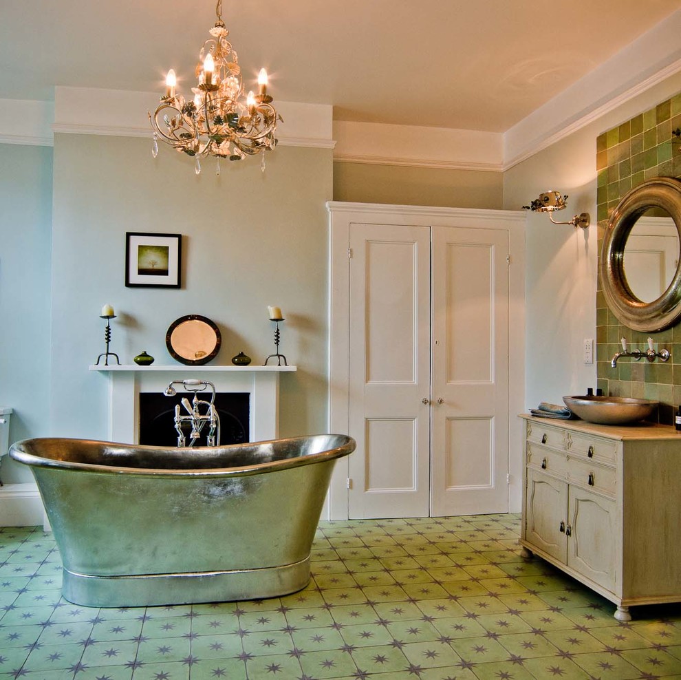Photo of a large traditional ensuite bathroom in Sussex with a vessel sink, freestanding cabinets, light wood cabinets, a freestanding bath, a built-in shower, green tiles, green walls and concrete flooring.