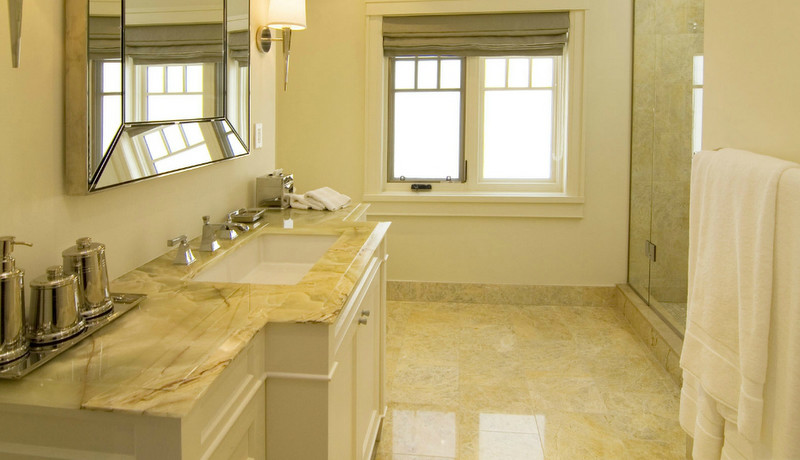 Inredning av ett klassiskt mycket stort badrum, med ett undermonterad handfat, luckor med infälld panel, vita skåp, bänkskiva i onyx, en hörndusch, en toalettstol med hel cisternkåpa, flerfärgad kakel, stenkakel, vita väggar och marmorgolv
