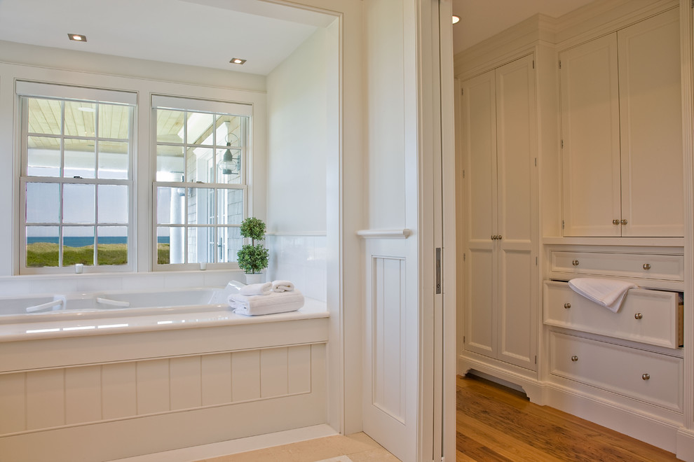 Imagen de cuarto de baño tradicional con puertas de armario blancas, bañera encastrada, baldosas y/o azulejos blancos y armarios con paneles empotrados