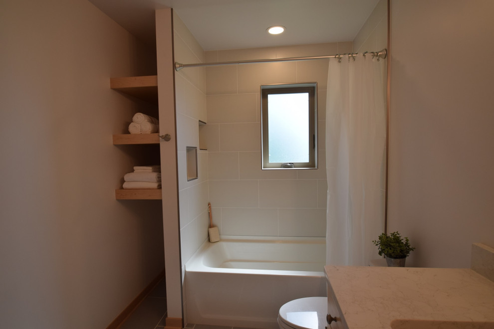 Idée de décoration pour une salle de bain tradition en bois clair de taille moyenne avec un placard à porte shaker, une baignoire en alcôve, un combiné douche/baignoire, WC à poser, un carrelage beige, des carreaux de céramique, un mur beige, un sol en carrelage de céramique, un lavabo encastré, un plan de toilette en quartz modifié, un sol gris, une cabine de douche avec un rideau, un plan de toilette beige et meuble simple vasque.