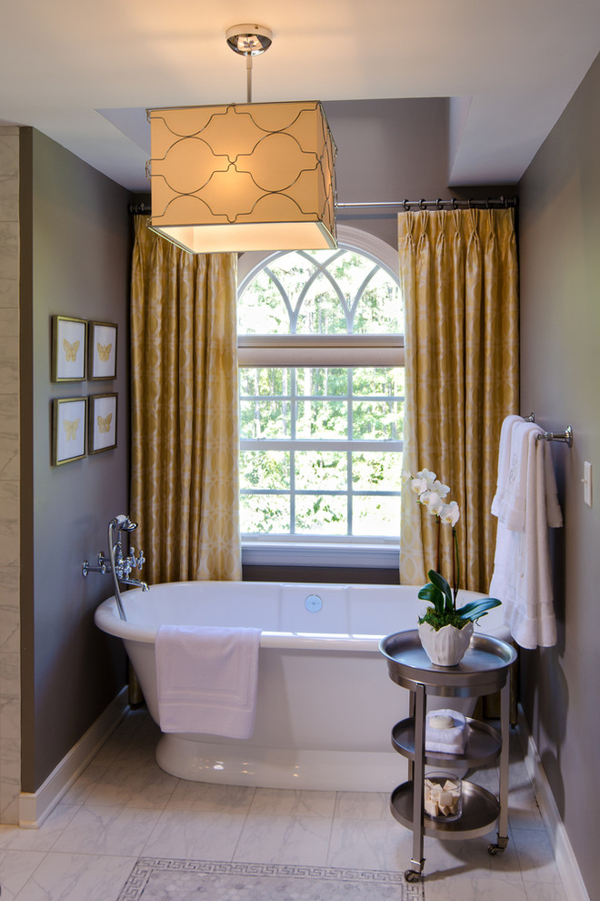 Cette image montre une salle d'eau traditionnelle de taille moyenne avec une baignoire indépendante, un mur gris et un sol en marbre.
