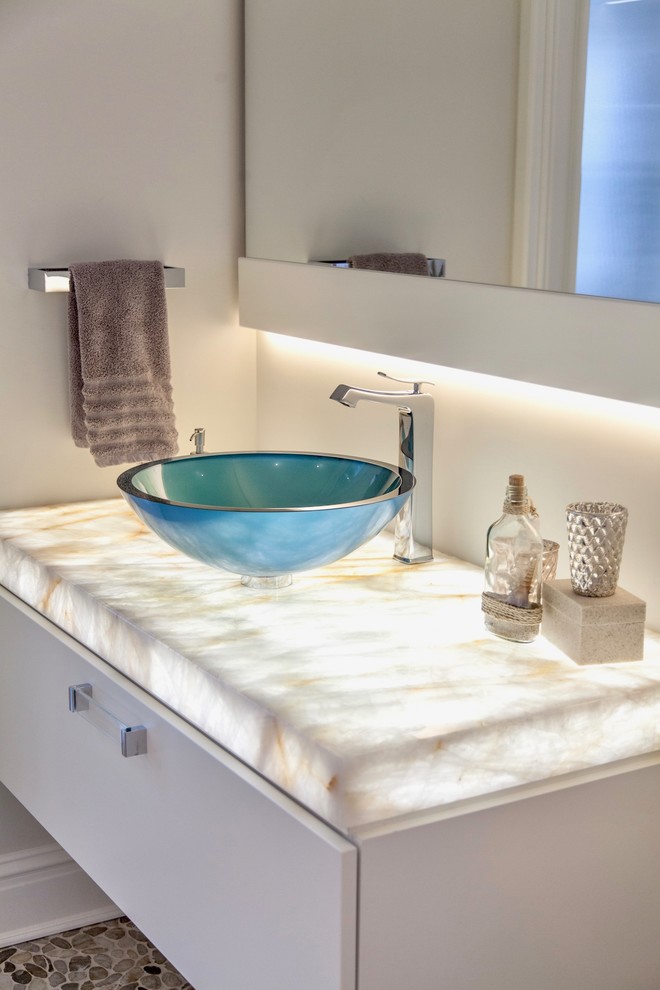 Bathroom - modern pebble tile floor bathroom idea in Other with flat-panel cabinets, white cabinets, white walls, a vessel sink, onyx countertops and white countertops