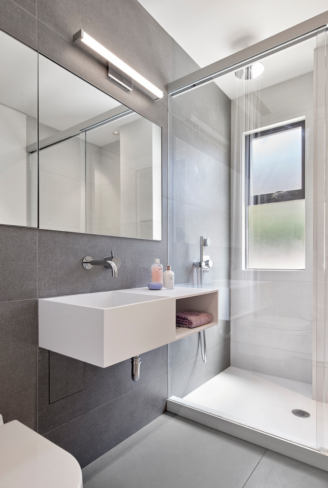 Inspiration för små moderna vitt badrum med dusch, med öppna hyllor, vita skåp, en dusch i en alkov, en vägghängd toalettstol, grå kakel, ett integrerad handfat, grått golv och dusch med skjutdörr