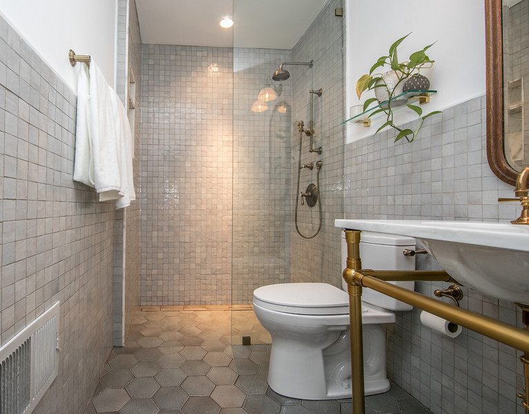 Inredning av ett klassiskt mellanstort vit vitt badrum med dusch, med vita skåp, en kantlös dusch, en toalettstol med separat cisternkåpa, grå kakel, perrakottakakel, grå väggar, klinkergolv i keramik, ett undermonterad handfat, marmorbänkskiva, grått golv och med dusch som är öppen