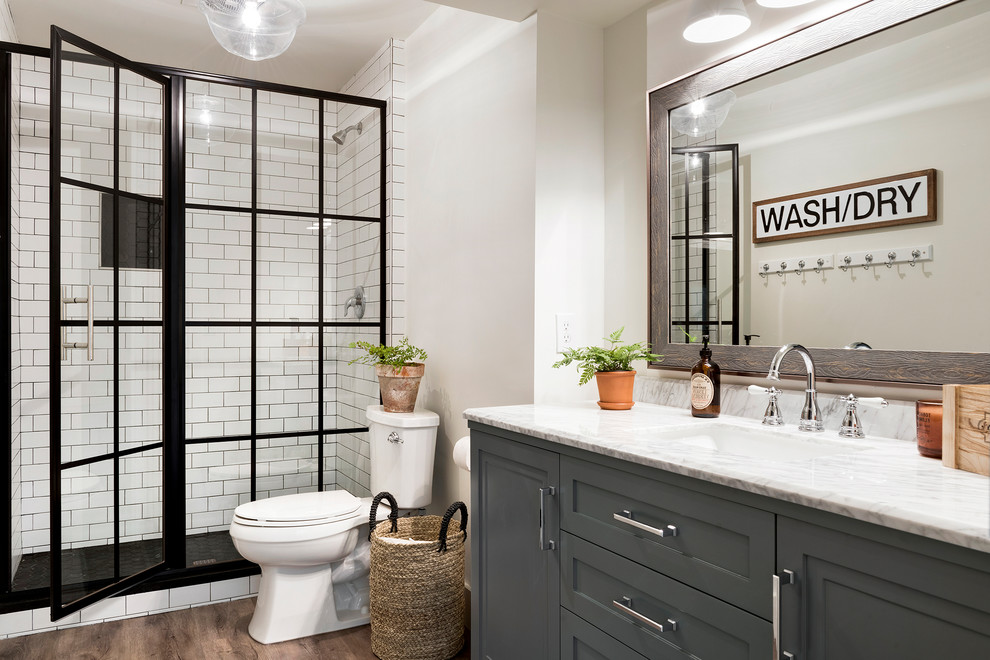 Inspiration for a cottage 3/4 white tile and subway tile medium tone wood floor and brown floor bathroom remodel in Minneapolis with white walls, shaker cabinets, gray cabinets, an undermount sink and white countertops