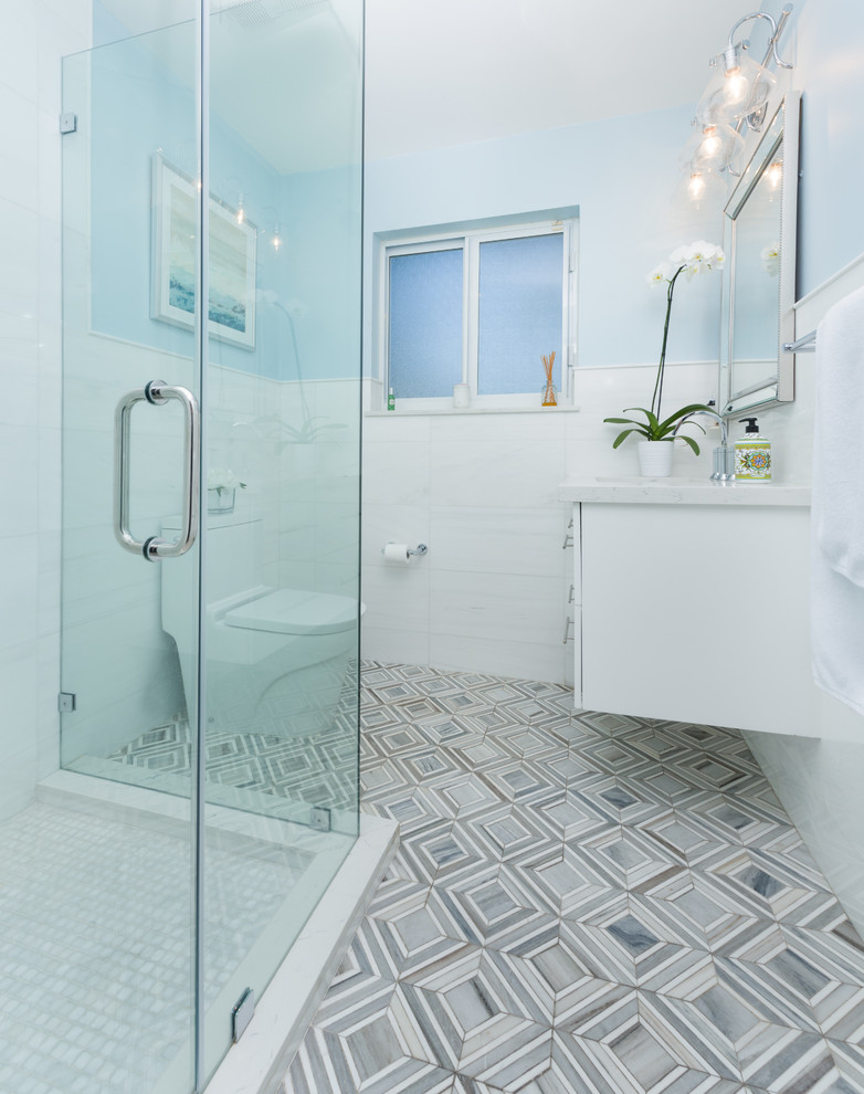 Foto på ett vintage badrum, med släta luckor, vita skåp, en hörndusch, en toalettstol med hel cisternkåpa, vit kakel, blå väggar, mosaikgolv, ett undermonterad handfat, flerfärgat golv och dusch med gångjärnsdörr